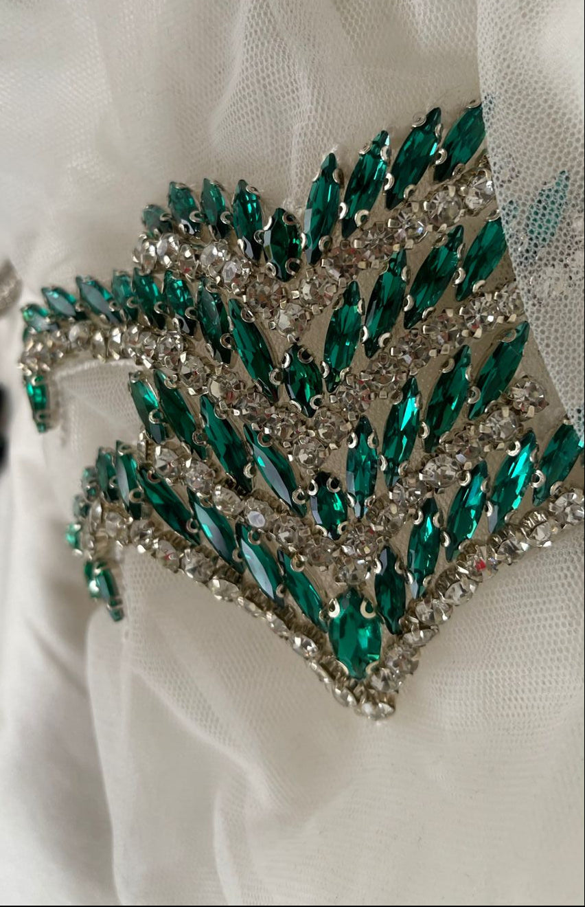 Green and silver decorative brooch on a white fabric background