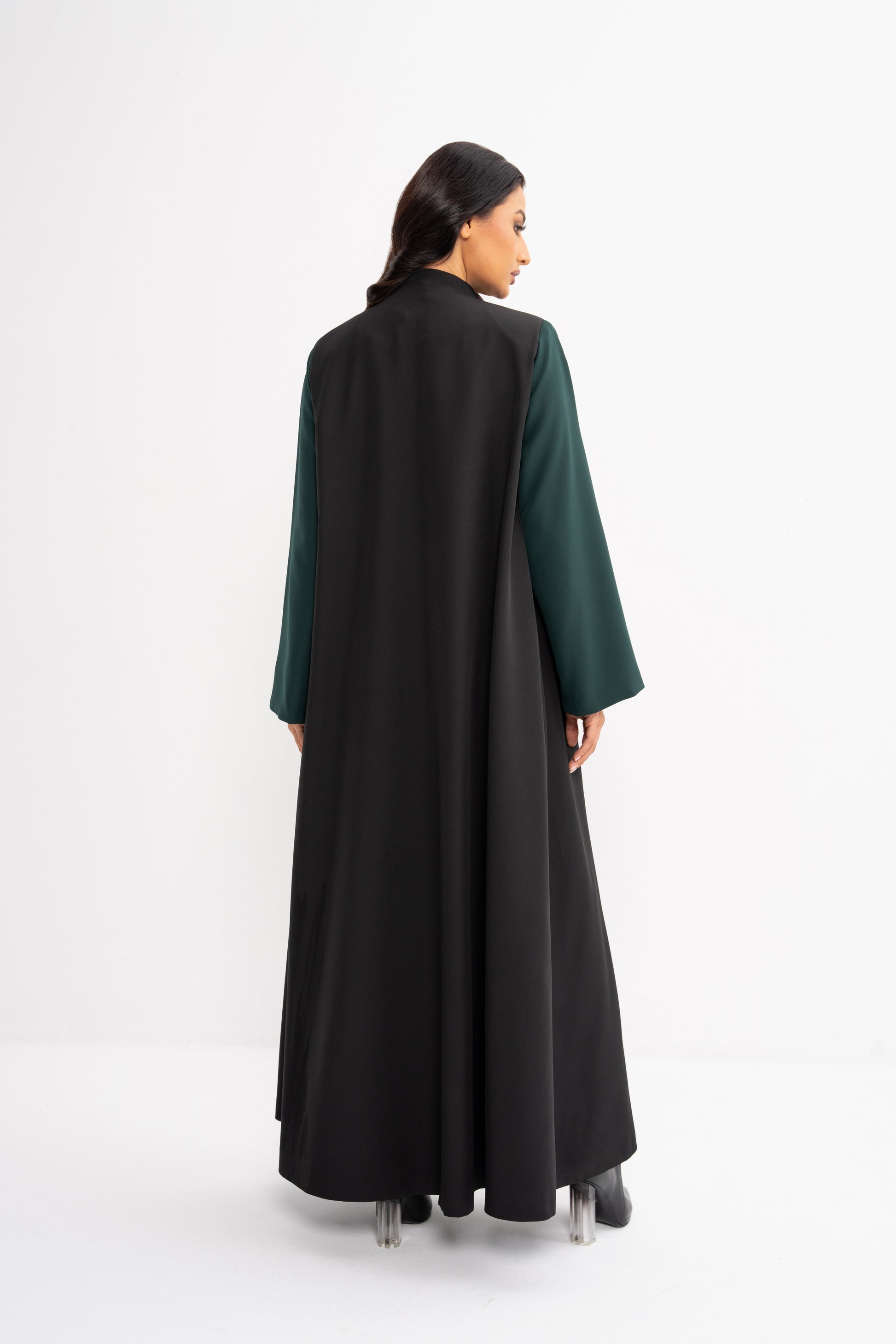 Woman wearing a black and green abaya on a white background