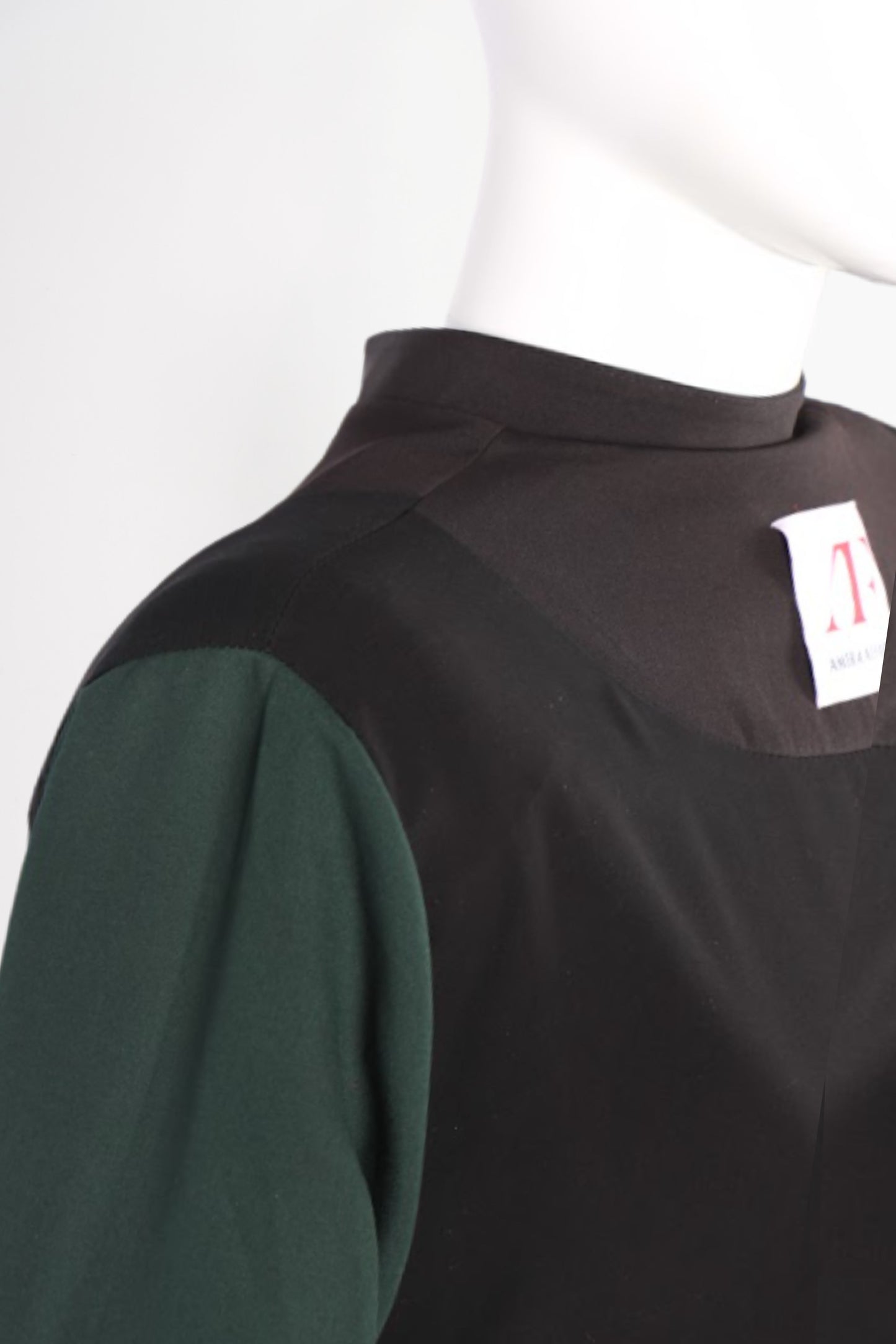Black and green garment on a mannequin with a visible tag.