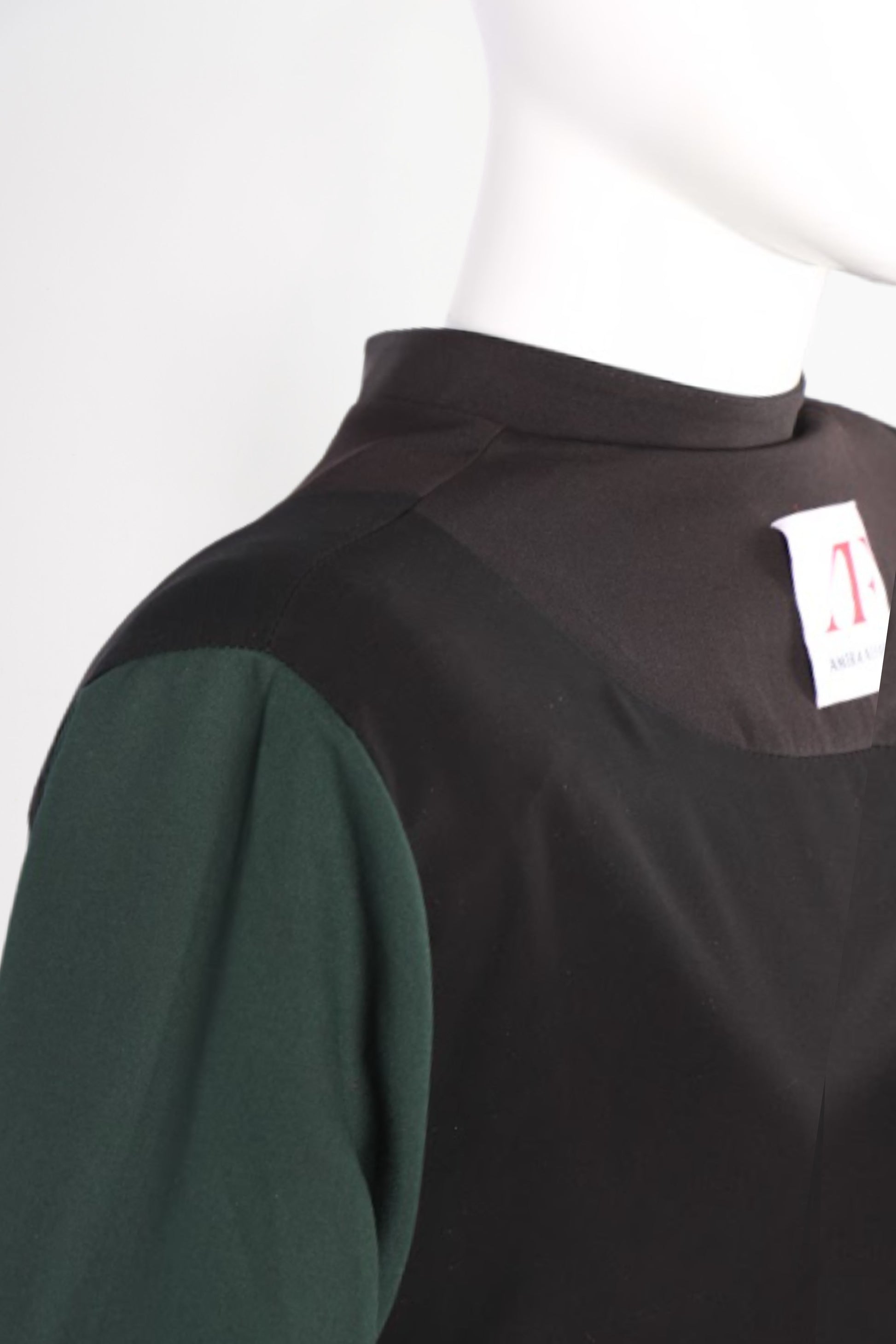 Black and green garment on a mannequin with a visible tag.